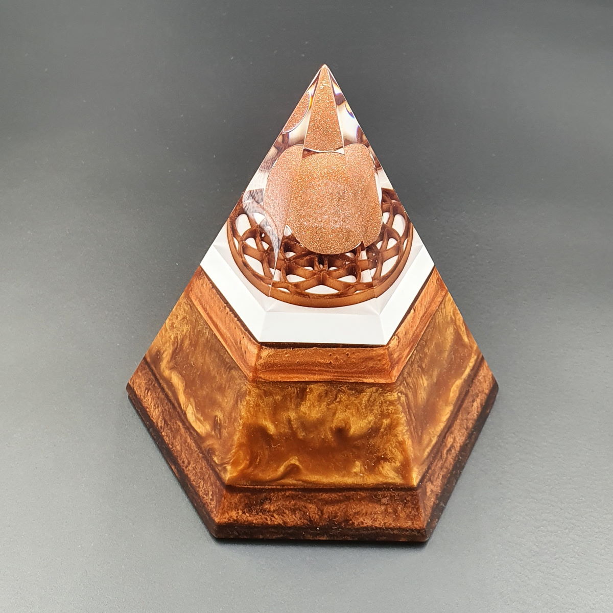 Šestkotna orgonit piramida iz kristalov sončev kamen, granat in črni turmalin, s simbolom roža življenja 